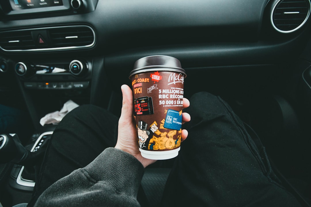 a-person-holding-a-cup-of-coffee-in-a-car-6lylzojbrya